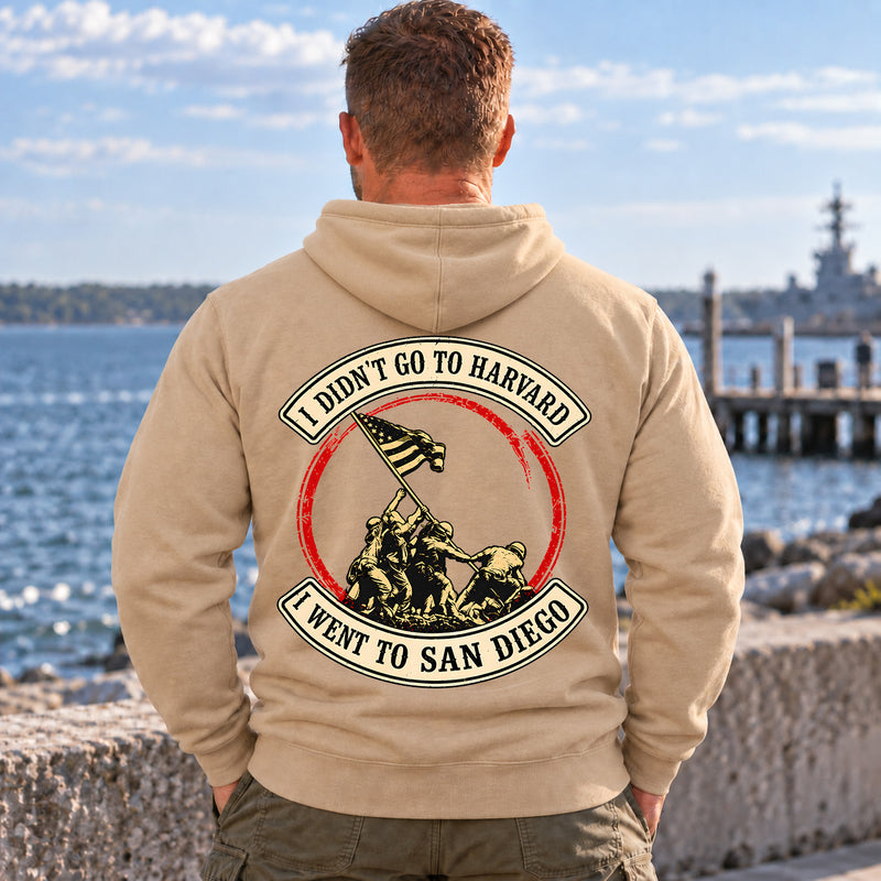 Man wearing a sand San Diego veteran hoodie, back print view, on the waterfront