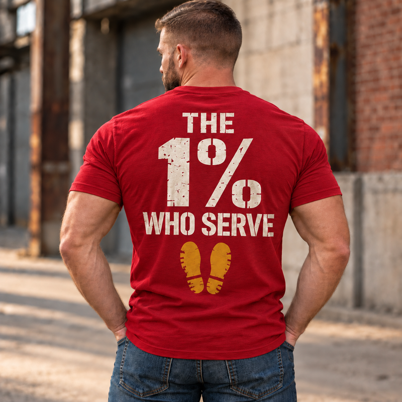 Man wearing a red The 1% veteran T-shirt, back print view, brick warehouse alley