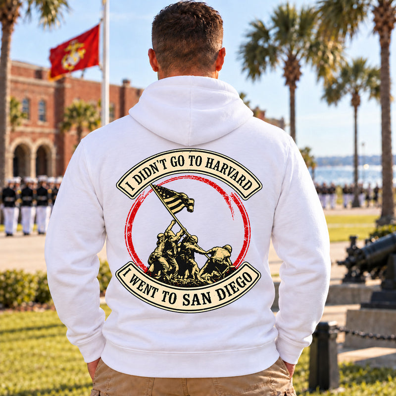 Man wearing a white San Diego veteran hoodie, back print view, outside a brick building