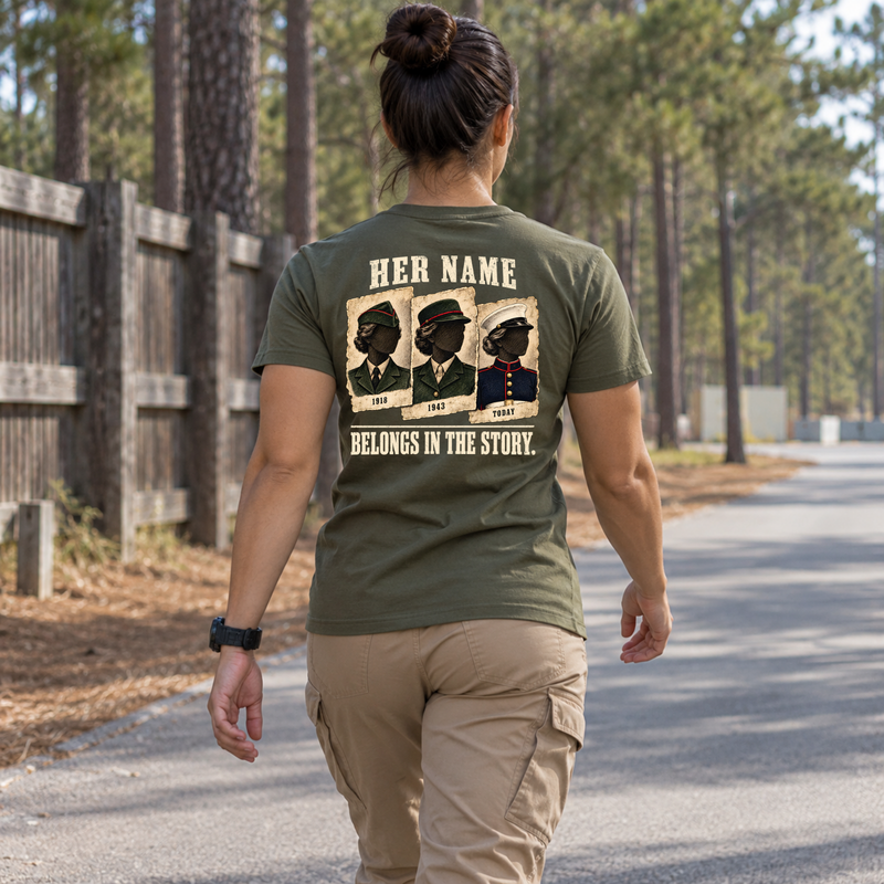Woman wearing military green Her Name Belongs in the Story Marine t-shirt on tree-lined path
