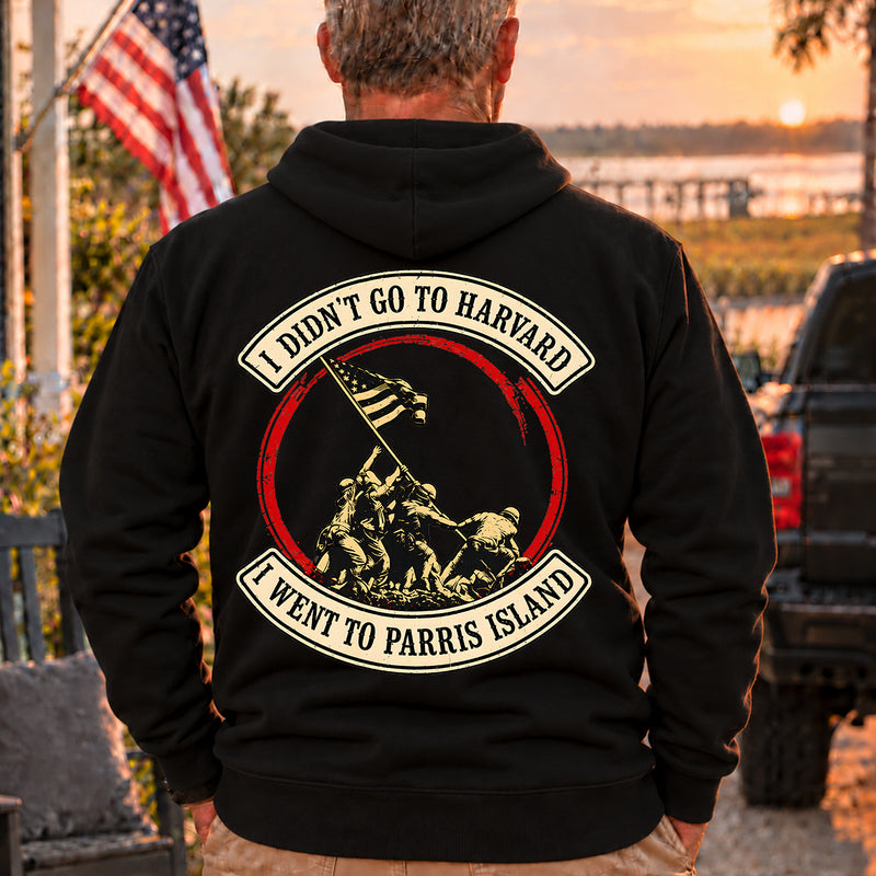 Man wearing a black Parris Island veteran hoodie, back print view, at sunset by the water