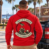 Man wearing a red Parris Island veteran hoodie, back print view, next to a pickup truck