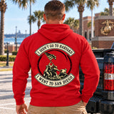 Man wearing a red San Diego veteran hoodie, back print view, next to a pickup truck