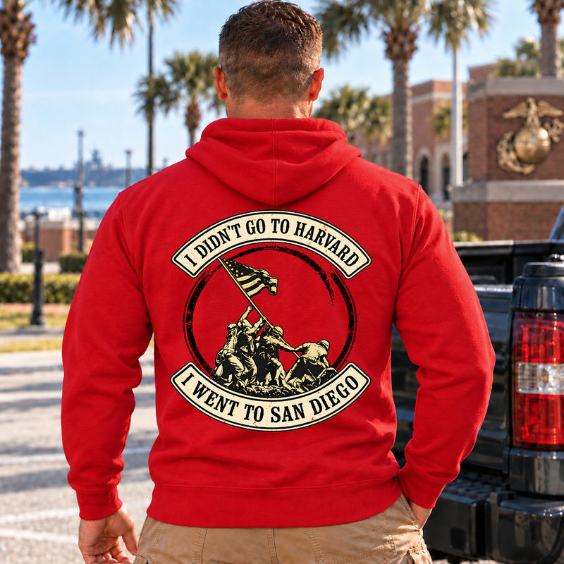 Man wearing a red San Diego veteran hoodie, back print view, next to a pickup truck