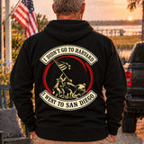 Man wearing a black San Diego veteran hoodie, back print view, at sunset by the water