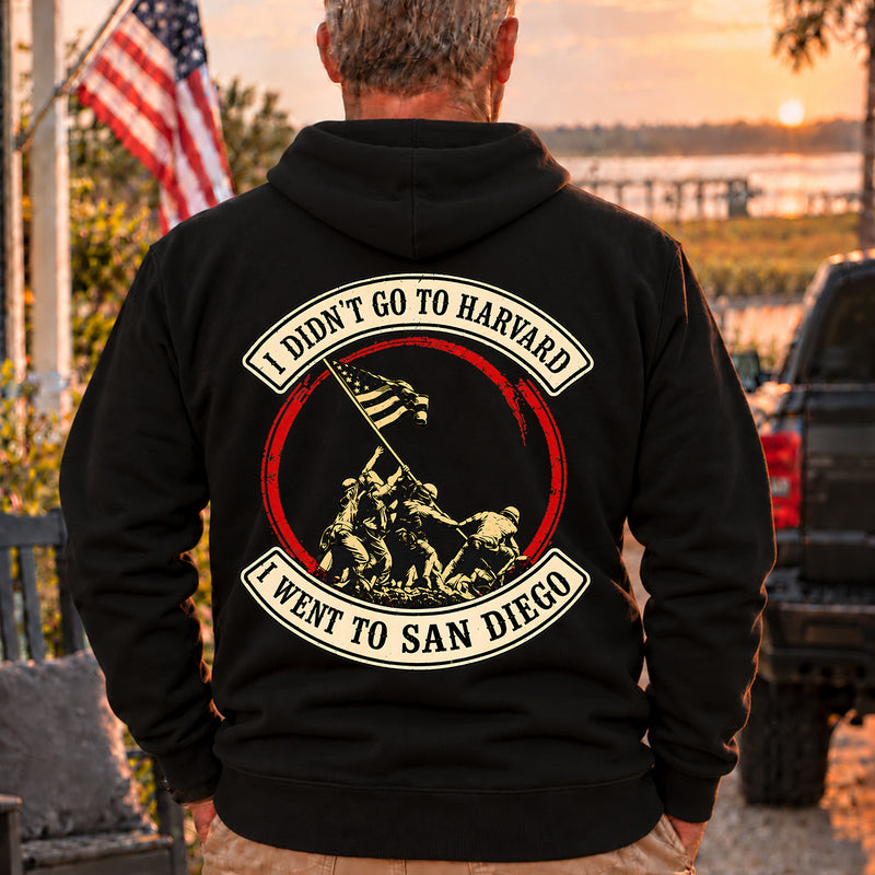 Man wearing a black San Diego veteran hoodie, back print view, at sunset by the water
