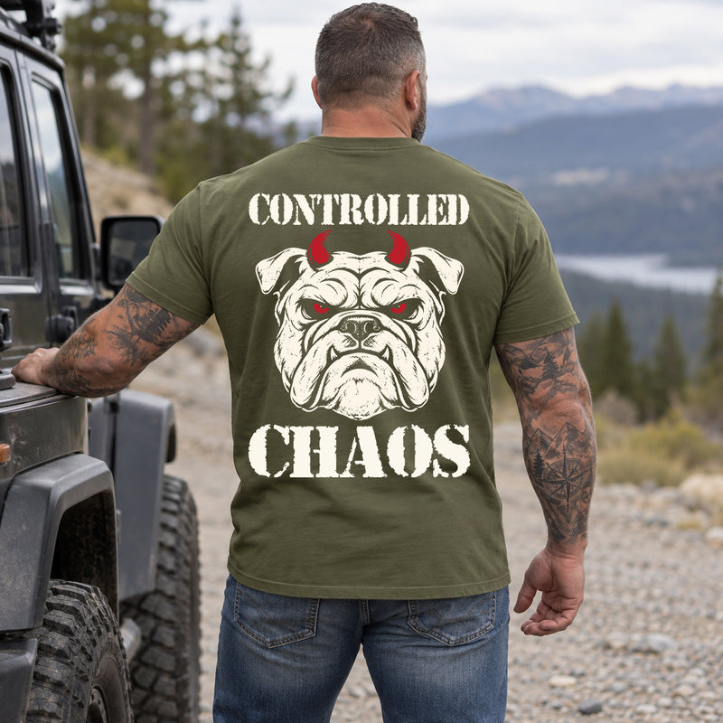 Man wearing a military green CONTROLLED CHAOS veteran T-shirt, back print view, mountain overlook beside an off-road truck