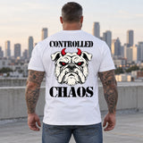 Man wearing a white CONTROLLED CHAOS veteran T-shirt, back print view, rooftop overlooking a city skyline