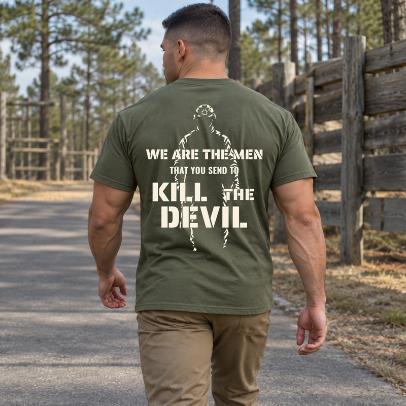 Man wearing a military green Kill The Devil custom year veteran T-shirt, back print view, walking a road past pine trees