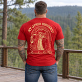 Man wearing a red My Other Birthday custom year veteran T-shirt, back print view, wooden deck above a pine forest