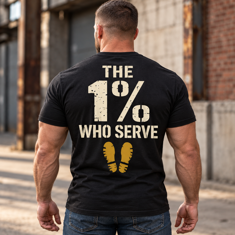 Man wearing a black The 1% veteran T-shirt, back print view, brick warehouse alley