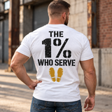 Man wearing a white The 1% veteran T-shirt, back print view, brick warehouse alley