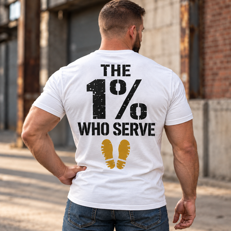Man wearing a white The 1% veteran T-shirt, back print view, brick warehouse alley
