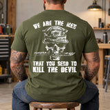 Man wearing a military green We are the men veteran T-shirt, back print view, workshop with tool cabinets and shelves