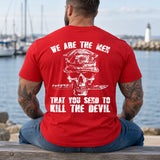 Man wearing a red We are the men veteran T-shirt, back print view, marina bench with a lighthouse beyond