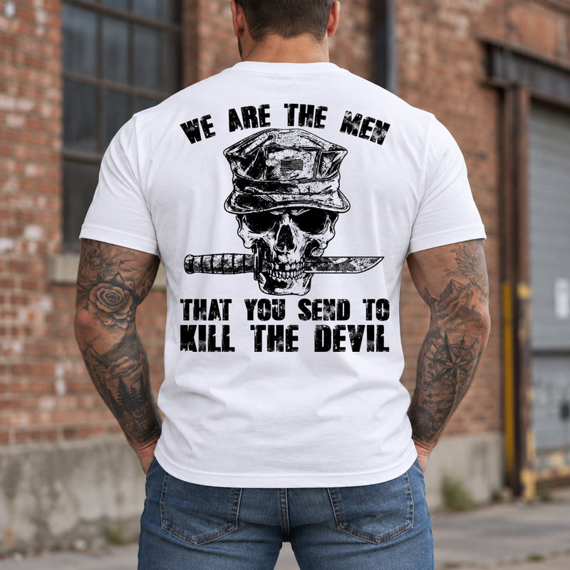 Man wearing a white We are the men veteran T-shirt, back print view, brick warehouse with tall windows