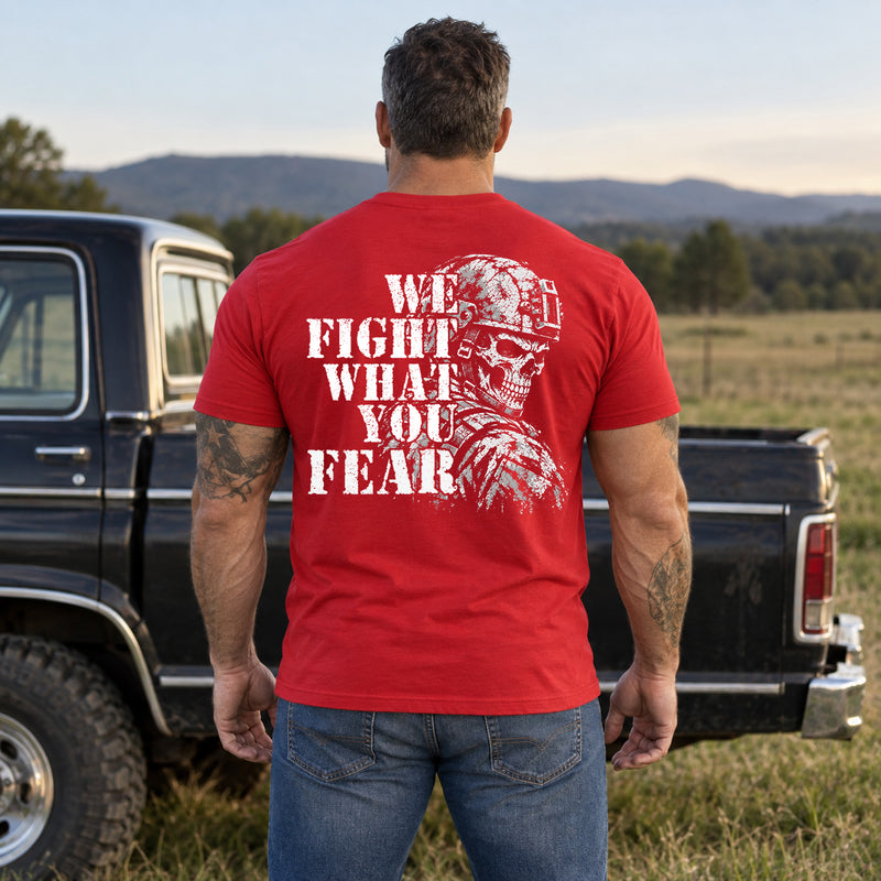 Man wearing a red We Fight What You Fear custom year veteran T-shirt, back print view, open field beside a pickup truck