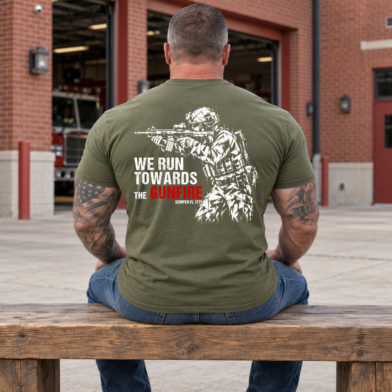 Man wearing a military green We Run Towards the Gunfire custom year veteran T-shirt, back print view