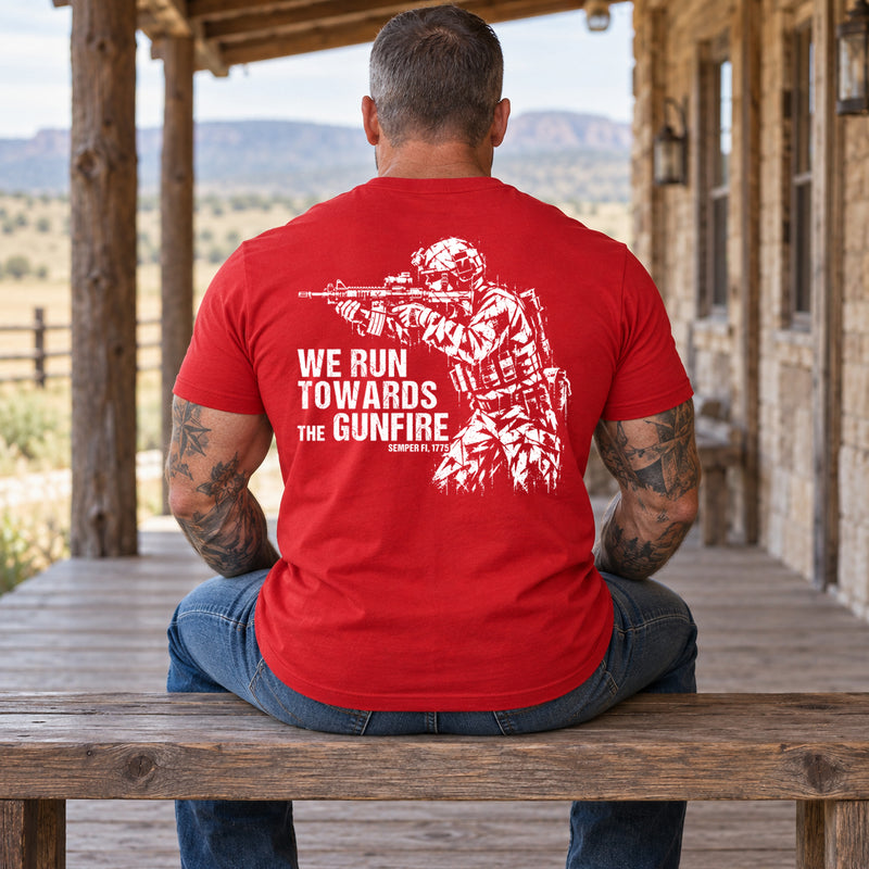 Man wearing a red We Run Towards the Gunfire custom year veteran T-shirt, back print view